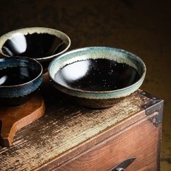 Bols japonais Migawa en grès noir et bleu océan sur un coffre en bois