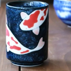 Tasse yunomi KOÏ posée sur une table en bois, à côté d’un bol bleu