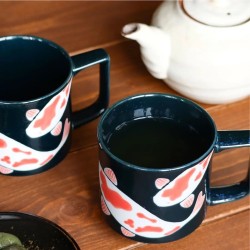 Deux mugs KOÏ remplis de thé vert sur une table en bois, à côté d’une théière