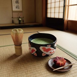 Bol à matcha KOÏ rempli de matcha fouetté sur un tatami, avec fouet en bambou et wagashi